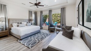 Een moderne slaapkamer met een groot bed, een plafondventilator en uitzicht op de omgeving.