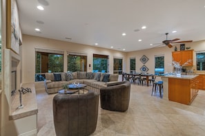 A spacious living area with a large sectional sofa, a round coffee table, and a dining area with a table and chairs.