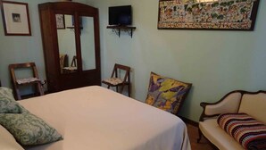 Une chambre à coucher comprenant un lit, deux chaises, un canapé, un téléviseur et un élément décoratif mural.