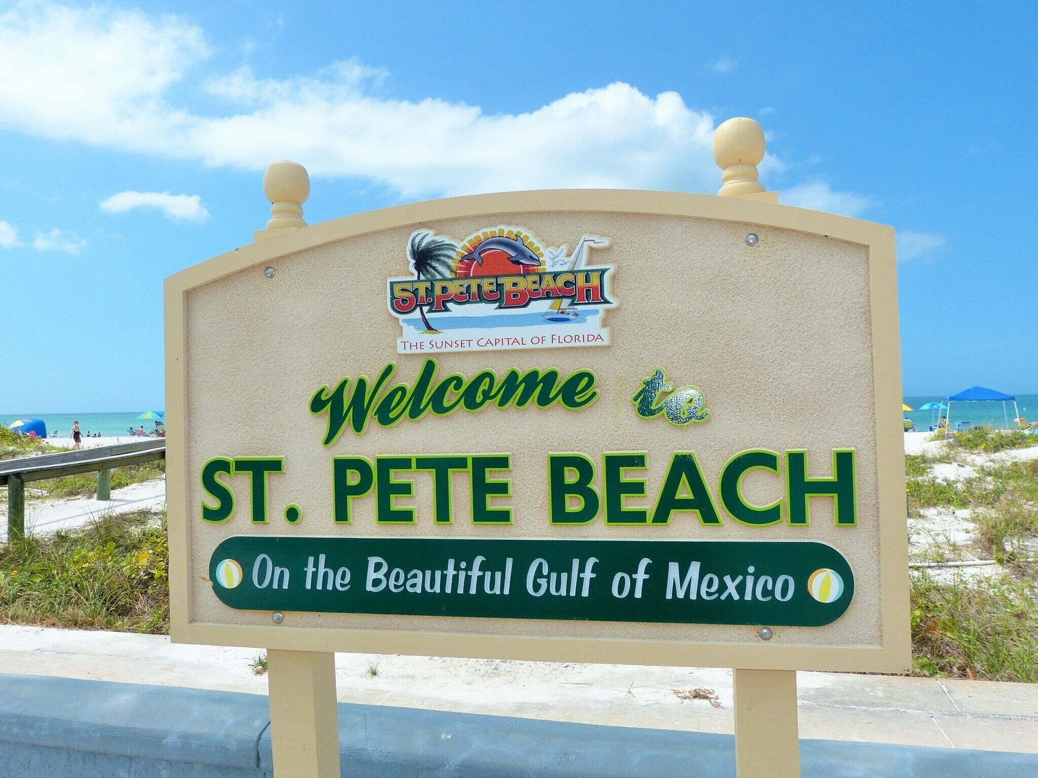 A welcome sign for St. Pete Beach, Florida, with a beach and ocean in the background.