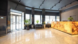 A modern lobby with a reception desk, seating area, and large windows. - Hotel Harmony (Prague)