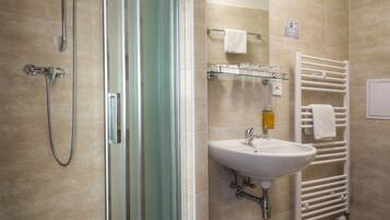 A modern bathroom with a glass shower enclosure, a white sink, and a towel rack.