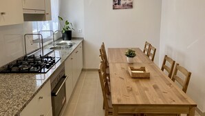Et moderne køkken med granitbordplader, et træspisebord og en potteplante.
