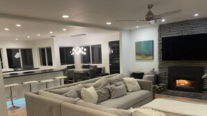 Een moderne woonkamer met een bank, een open haard, een eethoek en een keuken.