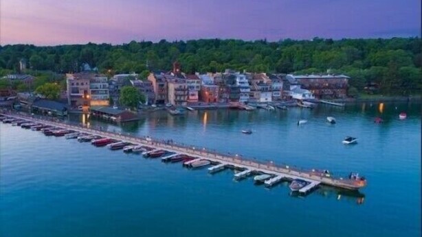 Een jachthaven aan het water met aangemeerde boten en gebouwen langs de oever.