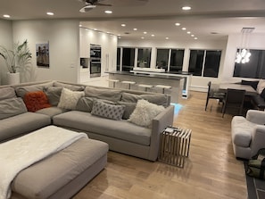 Ein modernes Wohnzimmer mit einem grauen Sofa, einem Couchtisch und einem Essbereich mit einem Holztisch und Stühlen.
