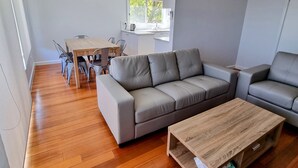 En moderne stue med en grå hjørnesofa, et træsofabord og et spiseområde med et træbord og stole.