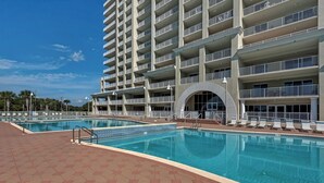 Um hotel com vários andares, piscina, área de estar ao ar livre e céu claro.