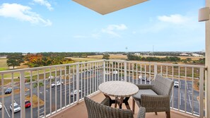 A balcony with a view of a parking lot and distant buildings.