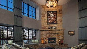 A spacious living room with a stone fireplace, large windows, and a cozy seating area.