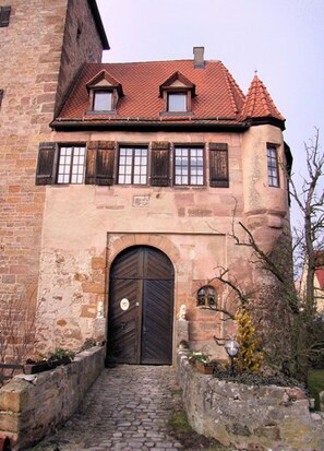 A historic building with a large central door, stone walls, and a red-tiled roof. - Romantic vacation apartment in a historic castle for 3-4 people (Nürnberg)