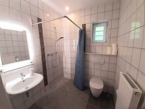 A bathroom with a shower, toilet, sink, and a window above the toilet. - A renovated former train station in an idyllic setting. Unique & cozy. (Vöhl/Herzhausen)