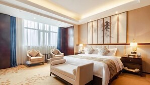 A spacious hotel room with a large bed, two bedside tables with lamps, a sofa, and a chair. - Timing International Hotel Zhoukou (Zhoukou)