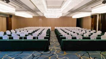 A conference room with rows of tables, each with a white chair and a water bottle.
