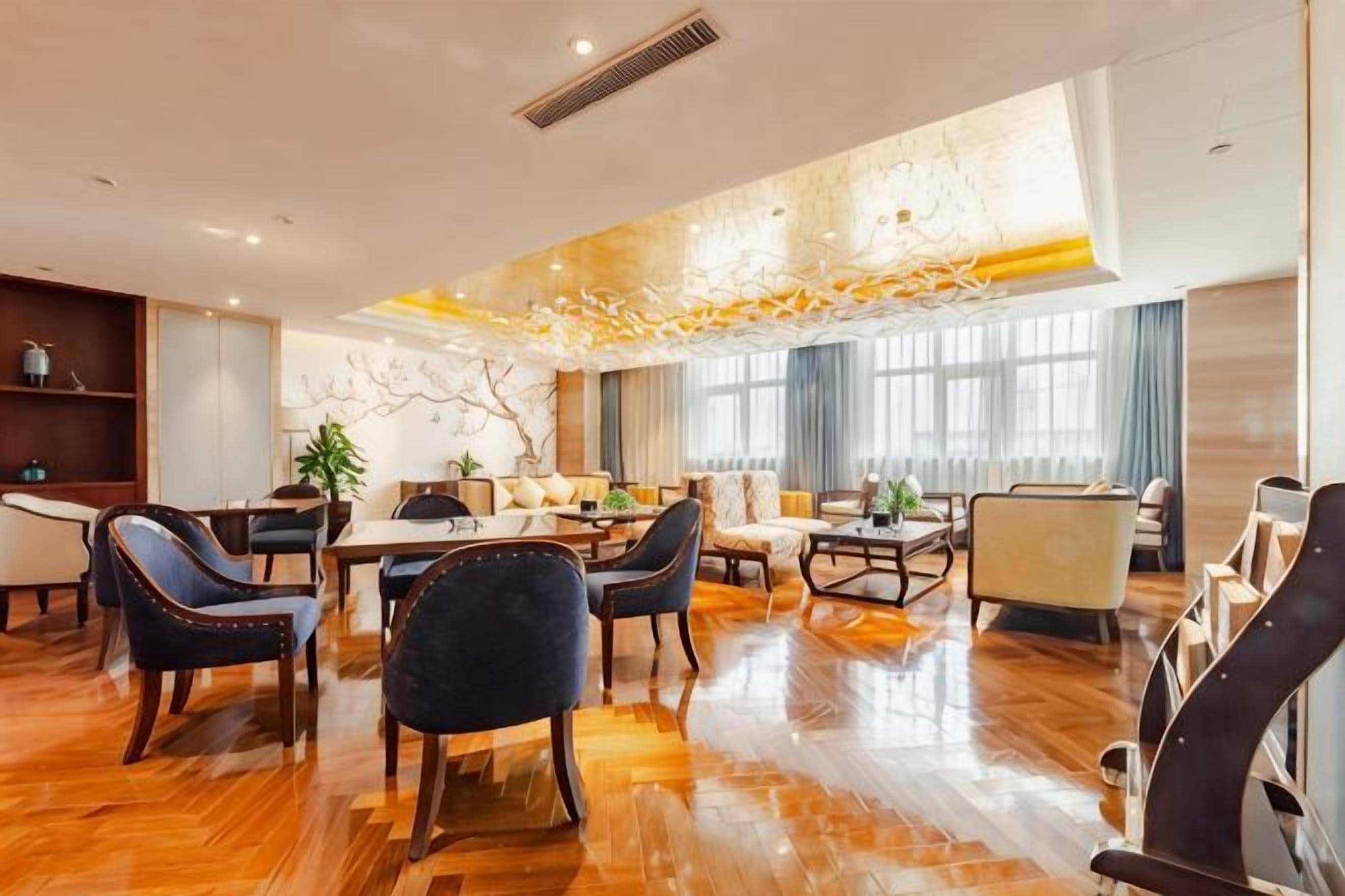 A spacious hotel lobby with a wooden floor, a central dining area, and seating arrangements.
