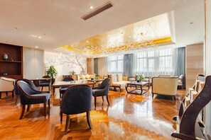 A spacious hotel lobby with a wooden floor, a central dining area, and seating arrangements. - Timing International Hotel Zhoukou (Zhoukou)