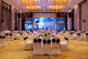 A conference room with rows of white chairs, a stage with a large screen, and a formal setting. - Timing International Hotel Zhoukou (Zhoukou)