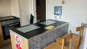 A compact kitchen with a stove, a sink, and a countertop with two placemats. - 1st Floor Hillview 2 Bedroomed Central Location (Burnham-on-Sea)