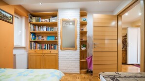 Un dormitorio con una cama grande, un armario de madera, una estantería y un espejo.