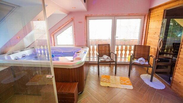 Un spa moderno con un jacuzzi, sillas de madera y un separador de vidrio.