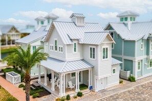 Ein Modell eines zweistöckigen Hauses mit Veranda, einem turmartigen Aufbau auf dem Dach und einer Palme im Vordergrund.