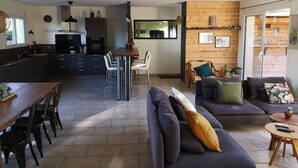 Una cocina moderna con armarios oscuros, una mesa de comedor de madera y una zona de bar.
