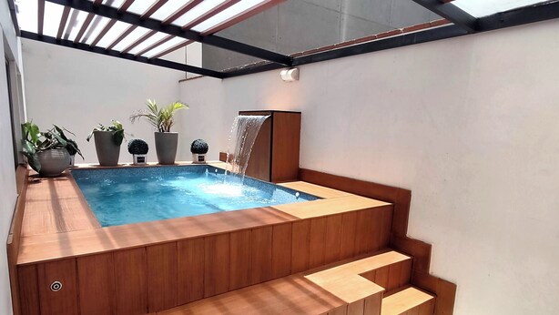 Un bain à remous avec des marches en bois et une petite cascade décorative.