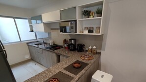 Une cuisine moderne dotée d’un plan de travail en granit, d’appareils électroménagers intégrés et d’un petit îlot central avec des tabourets.