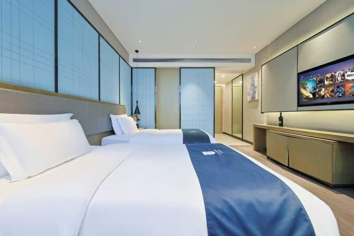 Quarto de hotel com uma cama grande, uma TV de tela plana e vista para a cidade.