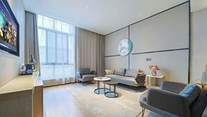 Una sala de estar moderna con un sofá, sillones, una mesa de centro y un televisor montado en la pared.