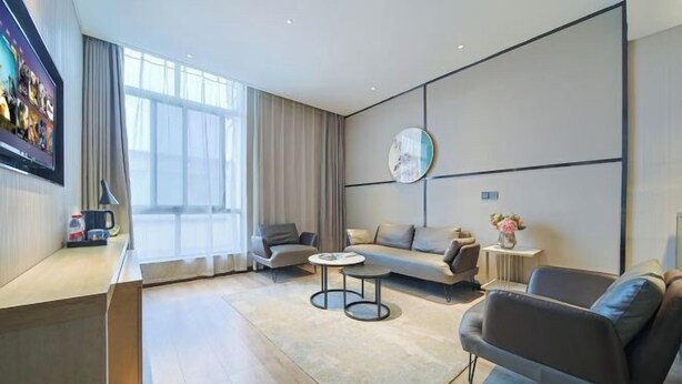 A modern living room with a sofa, armchairs, a coffee table, and a TV mounted on the wall. - Shangyi Hotel (Qianxi High speed Railway Station Branch) (Qianxi)