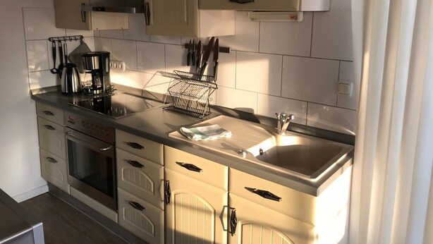 Una cocina moderna con estufa de acero inoxidable, cafetera y un mueble para cuchillos.