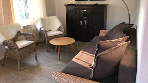 Una sala de estar con muebles de mimbre, un televisor y un mueble.