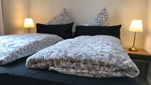 Cama doble con ropa de cama estampada y dos lámparas de noche.