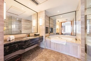 Un baño moderno con tocador de mármol, un espejo grande, bañera y zona de ducha.