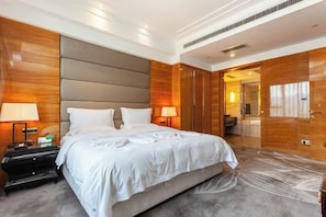 A modern hotel room with a large bed, wooden paneling, and a view of the bathroom. - Nine Dragon Hotel (Gaoping)