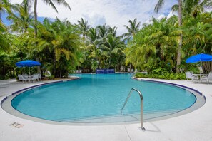 Una piscina circondata da palme e ombrelloni azzurri.