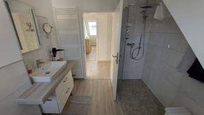Uma casa de banho moderna com chuveiro, pia e espelho.