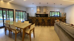Une cuisine moderne avec un mur de crédence en pierre, un coin repas avec une table et des chaises en verre, et un salon avec un canapé.