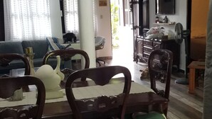 Un comedor con mesa y sillas de madera, una araña y un televisor montado en la pared.