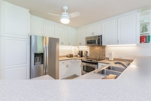 Una cocina moderna con armarios blancos, electrodomésticos de acero inoxidable, un microondas, un tostador y un lavabo.