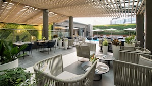 An outdoor seating area with wicker furniture, potted plants, and umbrellas. - K Hotel Douala (Douala)