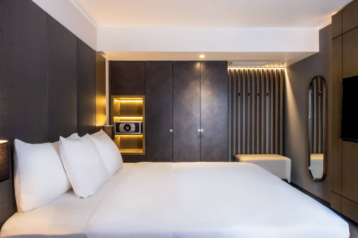 Una habitación de hotel moderna con una cama grande, un televisor de pantalla plana, sistema de sonido integrado y armario correderas.