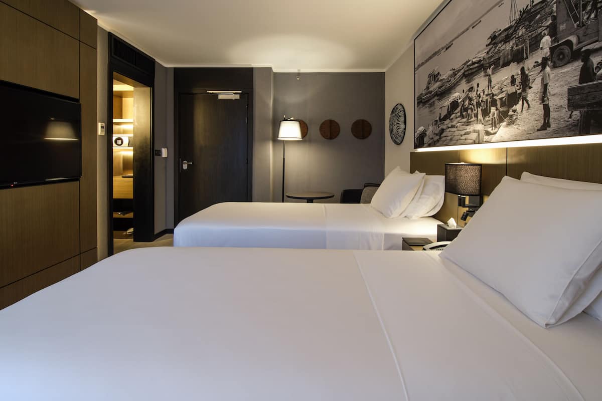 Habitación de hotel con dos camas, un televisor de pantalla plana, un cuadro en la pared y una lámpara.
