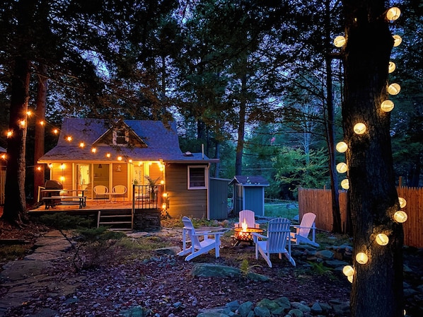 A cozy cabin with a porch, outdoor seating, and a fire pit.
