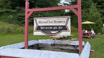 Une enseigne pour la brasserie Shrewd Fox, avec une table de pique-nique et des personnes en arrière-plan.