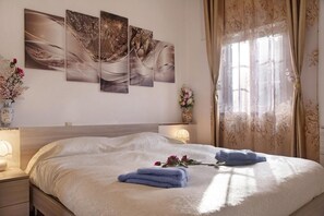 A neatly made bed with blue towels, a bedside lamp, and a floral vase on the nightstand. - AL CIOS VACATION HOME FOR A RELAXING VACATION IN THE GREEN OF NATURE (AZZIO VARESE)