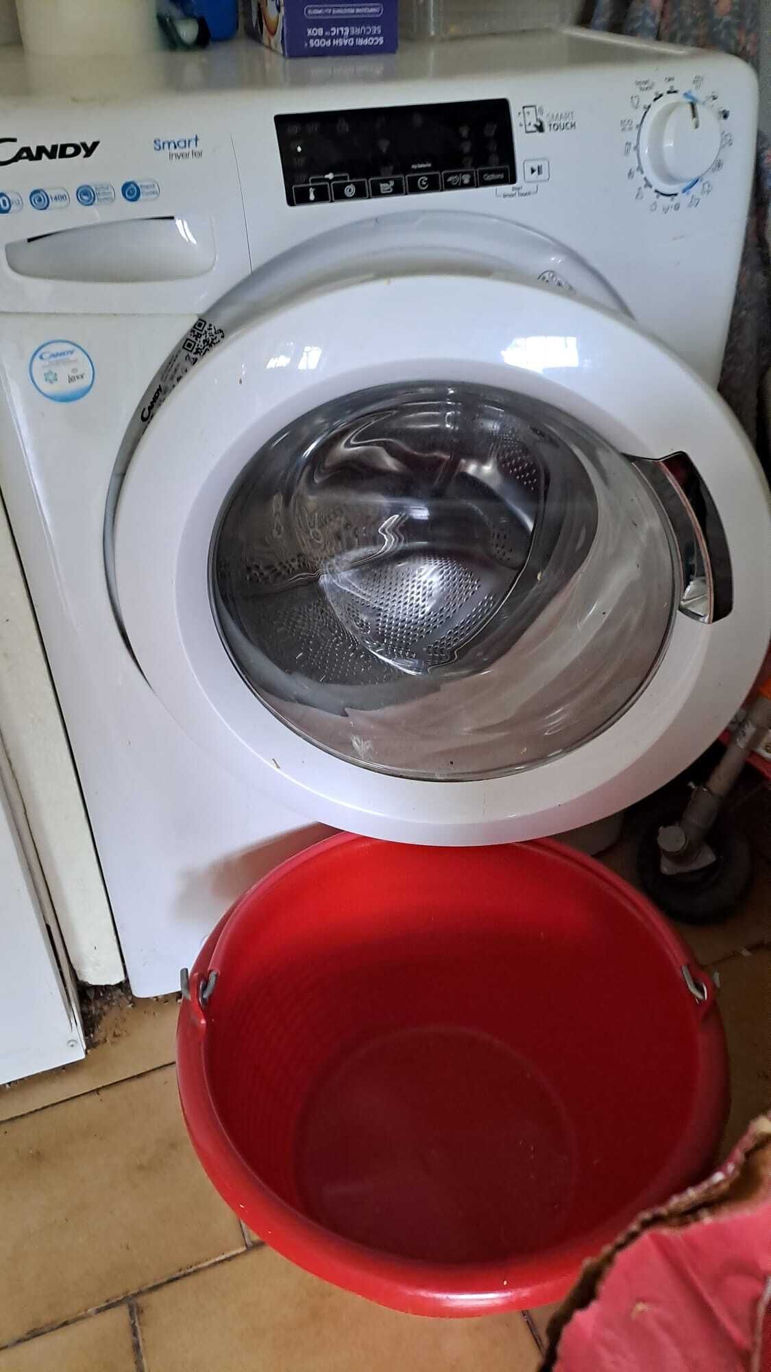 Una lavadora Candy Smart Inverter blanca con un cubo rojo colocado al frente.