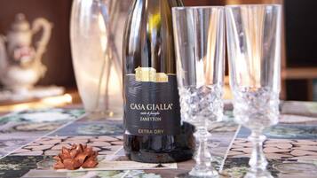Una botella de vino Casa Gialla Extra Dry Zannetton, dos copas y un lazo decorativo sobre una mesa de baldosas.