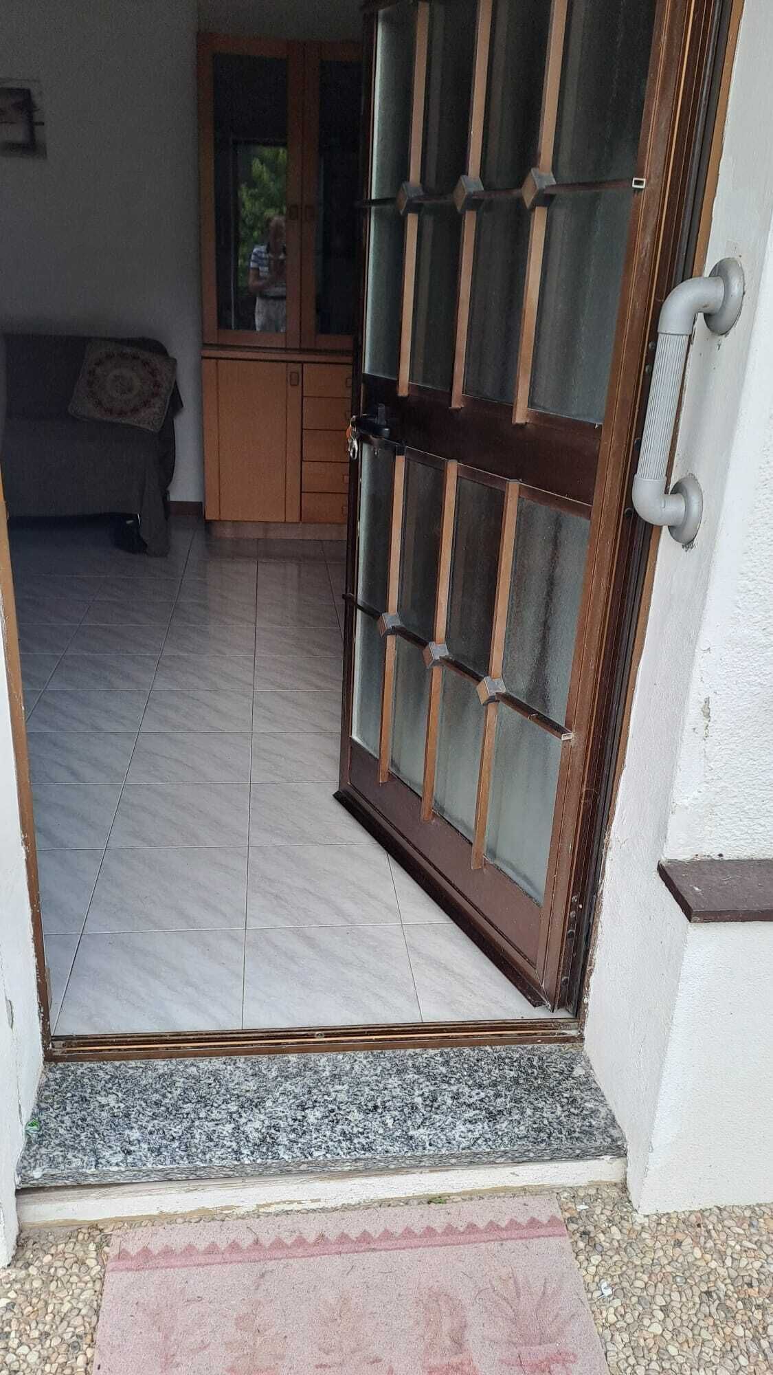 Una puerta que da a una habitación con suelo de baldosas, un armario de madera y una ventana.